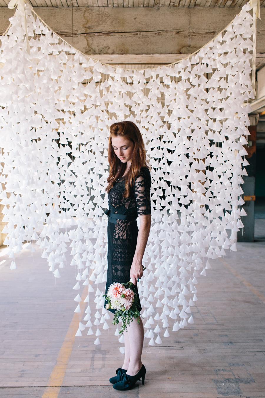 Lady posing with bouquet of flowers against wax paper backdrop in industrial site for photoshoot photobooth wedding contemporary style