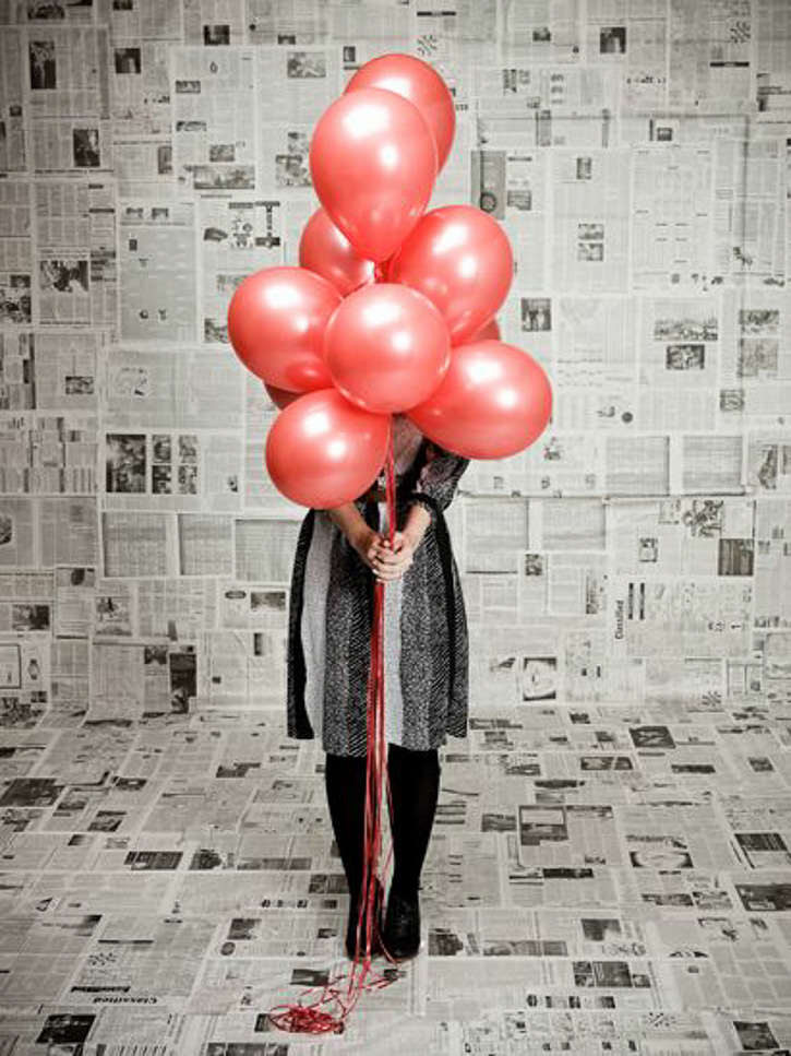 Woman posing with red balloons bunch in newspaper backdrop background for photoshoot photobooth