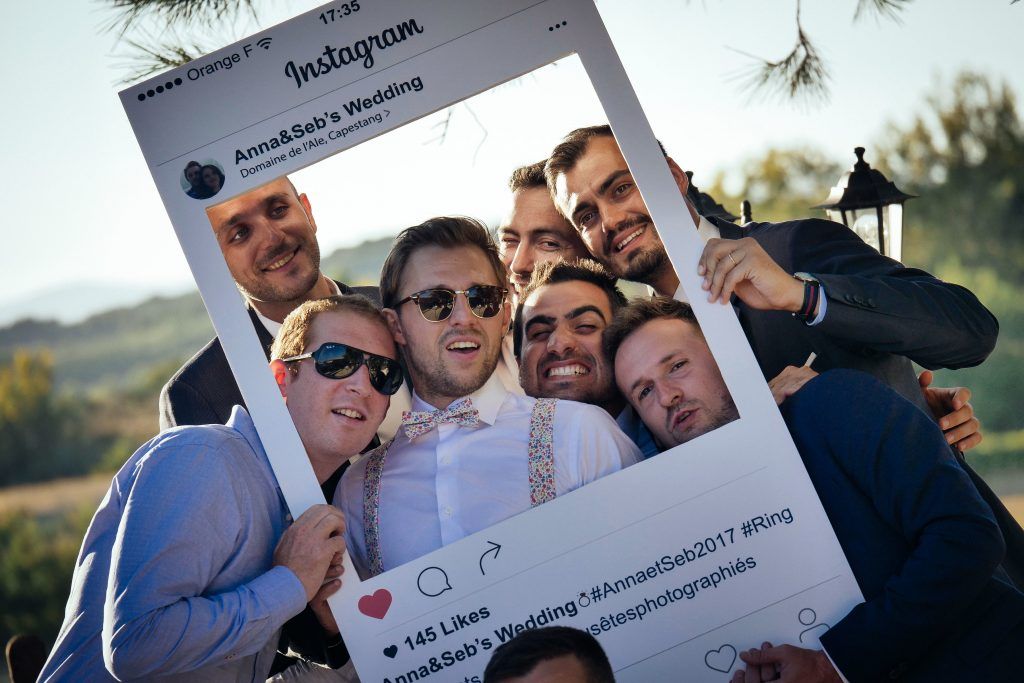 Group of guys posing together with cut-out frame instagram social media photoshoot at wedding photobooth gathering event