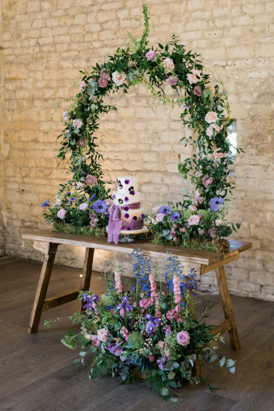 Wreath positioned on table with decorations against brick wall for photoshoot photobooth at wedding venue
